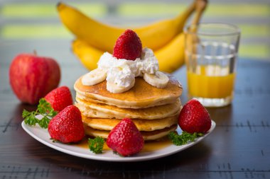 Krep kırbaç krem, çilek, muz, mutfak masasında portakal suyu bir bardak ile elma
