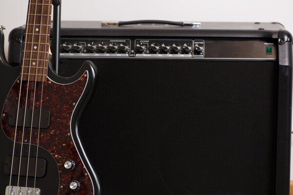 Bass guitar sitting next to an amp getting ready to play music live or in the studio.