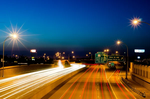 Vista de una carretera y paisaje urbano por la noche con senderos ligeros tomados con una velocidad de obturación lenta . Imagen de stock