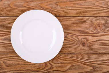Ahşap arka plan üzerinde beyaz yuvarlak tabak 