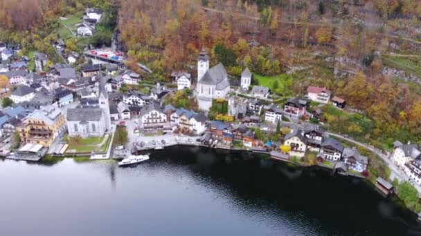 オーストリア北部のザルツカンマーグートにある有名な町ハルスタットの空中写真 湖や山の側面黄色の秋の木々に覆われた — ストック動画