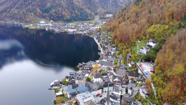 オーストリア北部のザルツカンマーグートにある有名な町ハルスタットの空中写真 湖や山の側面黄色の秋の木々に覆われた — ストック動画