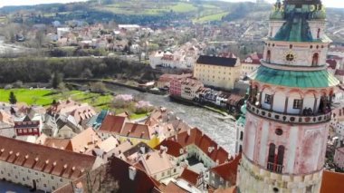 Cesky Krumlov Kalesi yakınlarında insansız hava aracı uçuruyor. Güneşli bir günde şehir manzarası ve kırmızı kiremitli çatılar. 4K Drone Videosu