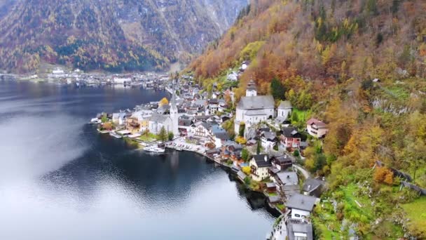 オーストリア北部のザルツカンマーグートにある有名な町ハルスタットの空中写真 湖や山の側面黄色の秋の木々に覆われた — ストック動画