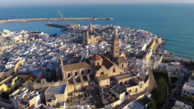 Deniz kenarında güzel bir İtalyan şehrinin hava görüntüsü. Eski Monopoli üzerinde İHA uçuşu. Deniz manzarası, evler ve kiliseler. Bari, Puglia, İtalya. 4K