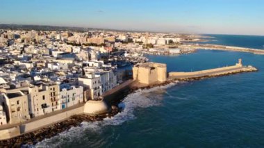 Deniz kenarında güzel bir İtalyan şehrinin havadan görünüşü. Kale manzarası, kiliseler ve sahildeki evler. Monopoli, Bari, Puglia, İtalya. 4K