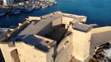 Monopoli, İtalya 'nın deniz kenarındaki şehri. Güneşli bir günde kalenin ve denizin havadan görünüşü. Bari, Puglia, İtalya 4K 'da.