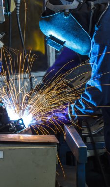 Metal ve kıvılcımlar üreten koruyucu maskeli kaynakçı. 