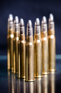 Bir bardak yansıma ile koyu mavi bir arka plan üzerinde Mühimmat. Yakından kapatın. Silah. Mermi 