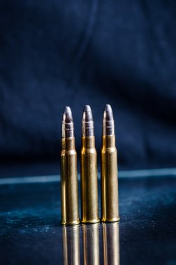 Bir bardak yansıma ile koyu mavi bir arka plan üzerinde Mühimmat. Yakından kapatın. Silah. Mermi 