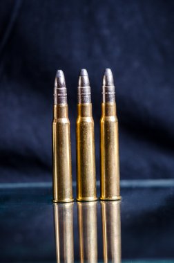 Bir bardak yansıma ile koyu mavi bir arka plan üzerinde Mühimmat. Yakından kapatın. Silah. Mermi 