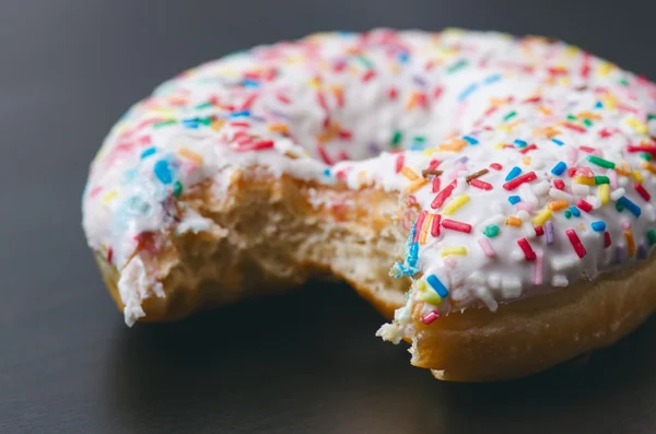 Donut mit Streusel und weißem Eis. Donuts Hintergrund. Kuchen und Süßes. Lebensmitteldetails. Nahaufnahme — Stockfoto