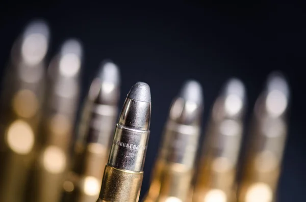 Munición sobre fondo azul oscuro con reflejo en un vaso. De cerca. Armas. Balas. — Foto de Stock