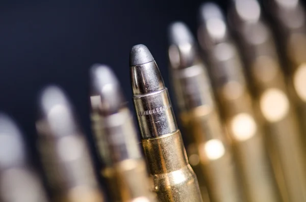 Munición sobre fondo azul oscuro con reflejo en un vaso. De cerca. Armas. Balas. — Foto de Stock