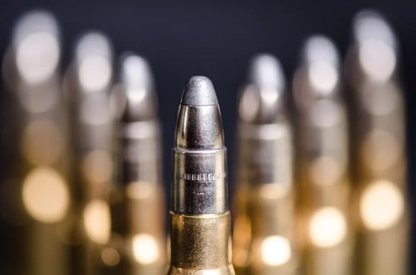 Munición sobre fondo azul oscuro con reflejo en un vaso. De cerca. Armas. Balas. — Foto de Stock