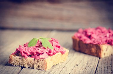 Pancar serpiştiği ahşap bir masanın üzerinde iki dilim ekmek. Doğal arka plan ve sağlıklı, vejetaryen ve vegan gıda. Hızlı kahvaltı. Çiğ yemek. Tarım 