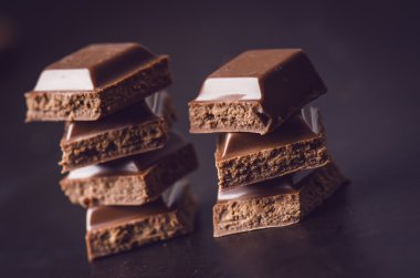 Karanlık bir arka plan üzerinde iki çikolata bina. enerji ve şeker. Kırık bar. Çikolata blok yığını 