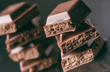 Karanlık bir arka plan üzerinde iki çikolata bina. enerji ve şeker. Kırık bar. Çikolata blok yığını 