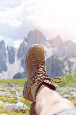 Adam yürüyüşçü bir yere uzanır. Arka plan gibi zirveler. Güneşli bir gün. Trekking botları. Lens parlaması. Başarılı backpacker bir görünüm keyfini çıkarın. 