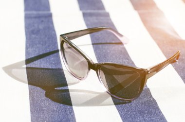 Battaniyenin üzerine siyah aynalı güneş gözlüğü. Gözlükten gölge. Güneş ışığı. Yaz konsepti 