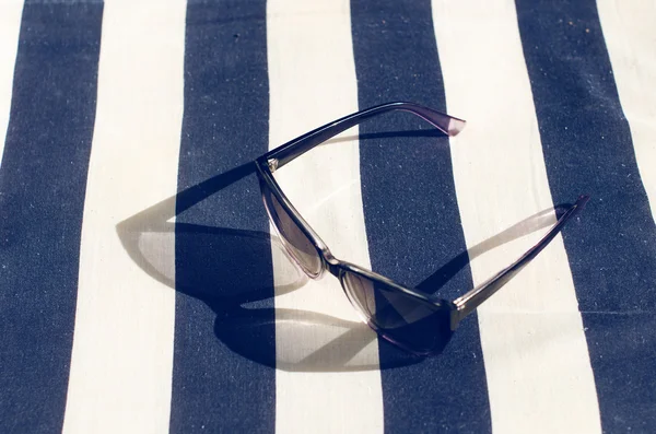 Battaniyenin üzerine siyah aynalı güneş gözlüğü. Gözlükten gölge. Güneş ışığı. Yaz konsepti 