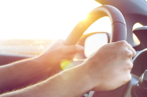 Gün doğumunda araba sürmek. Erkek elleri arabada bir süre tutmak. Sürüş. Güneş ışığı 