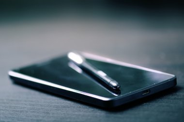 Akıllı telefonda kalem. Karanlık arka plan. Teknoloji mobil. 