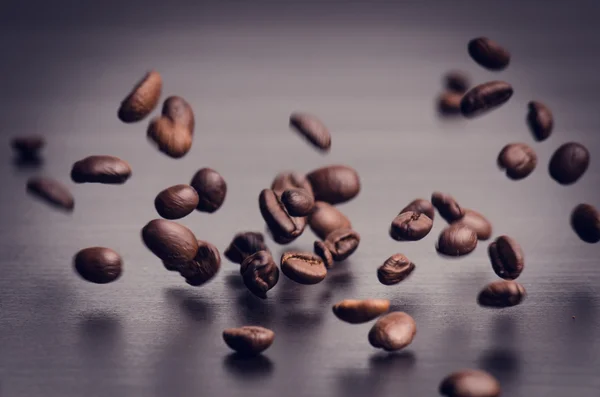 Grãos de café em um fundo preto. Levitação de grãos de café. Grãos de café crus. Produto granulado. Bebida quente. Fecha. Colheita. Fundo natural. Energia — Fotografia de Stock