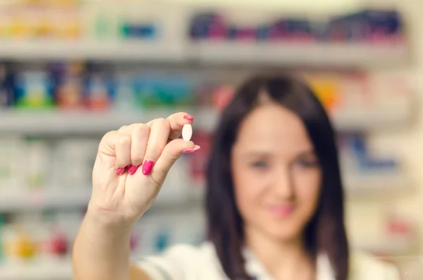 Kobieta chemik farmaceuta Pokaż pigułki. Apteka apteka jest podłoże. Ładny, młody laborant. — Zdjęcie stockowe