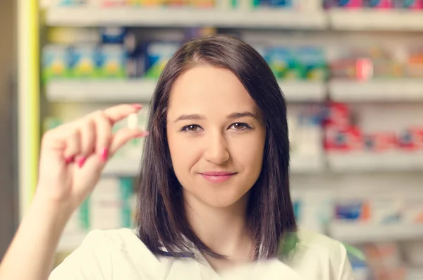 Kobieta chemik farmaceuta Pokaż pigułki. Apteka apteka jest podłoże. Ładny, młody laborant. — Zdjęcie stockowe
