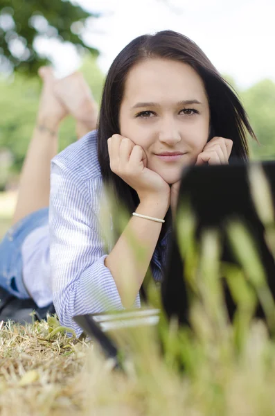 Vrouw met laptop liggen op een gras met laptop — Stockfoto