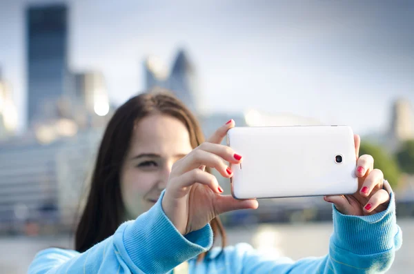 Mujer toma un selfie en una ciudad — Foto de Stock