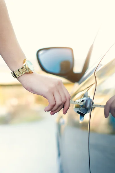 Woman with car key. Opening car door. Womans hand unlocking a door on a car. Sunlight. Transportation.
