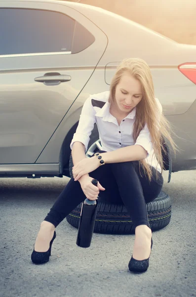 Mujer borracha sentada en un volante en coche. Una mujer bebe alcohol. Jovencita sexy. Repara un auto. Accidente de coche . — Foto de Stock