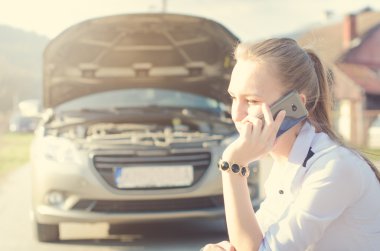 Kızı merak ettim. Bir arka plan üzerinde kırık araba. Üstünde a tekerlek kadın sit. Seksi genç kadın araç onarım. Doğal arka plan. Araba kazası