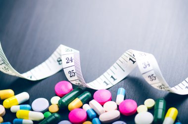 Eczane arka plan siyah bir tabloda teyp ölçme ile. Siyah bir zemin üzerine tablet. Hapları. Tıp ve sağlıklı. Kapsül kapatın. Aynı tür haplar 