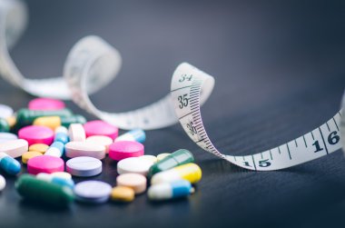 Eczane arka plan siyah bir tabloda teyp ölçme ile. Siyah bir zemin üzerine tablet. Hapları. Tıp ve sağlıklı. Kapsül kapatın. Aynı tür haplar 