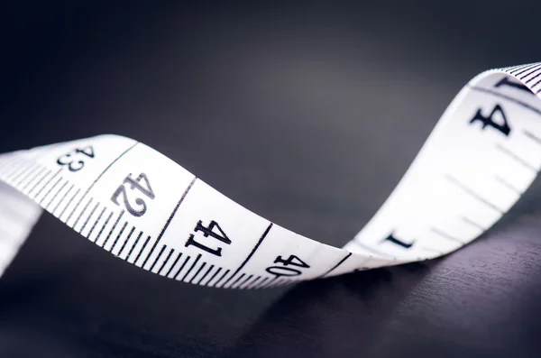 White measuring tape on a dark background. Rolled tape with numbers Royalty Free Stock Photos