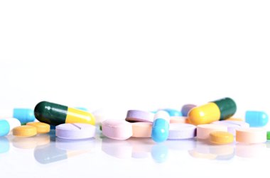 Beyaz bir arka plan üzerinde izole tabletleri. Bir cam haplarla yansımasıdır. İlaçlar arka plan. Eczane. Kapsül yakın çekim.