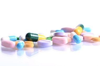 Beyaz bir arka plan üzerinde izole tabletleri. Bir cam haplarla yansımasıdır. İlaçlar arka plan. Eczane. Kapsül yakın çekim.