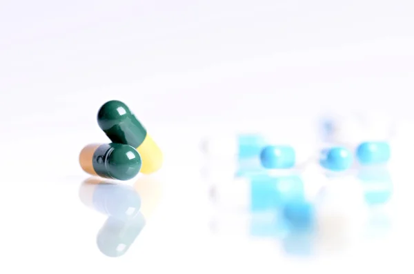 Tabletten geïsoleerd op een witte achtergrond. Reflectie van pillen op een glas. Geneesmiddelen achtergrond. Apotheek. Close up van capsules. — Stockfoto