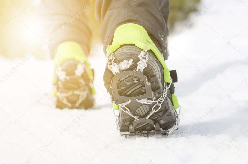 Hiking boots with equipment for ice on a snow background. Winter mountains. Sun light. Seasons sport. Hiker and tools for climbing and tourism