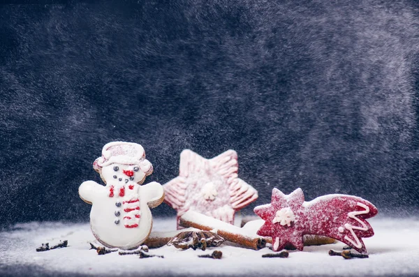 Christmas decoration and cookies. Storm and windy. Flour and spices for a christmas baking on a dark background. Snowman, stars, cinnamon, comet. — Stock Photo, Image