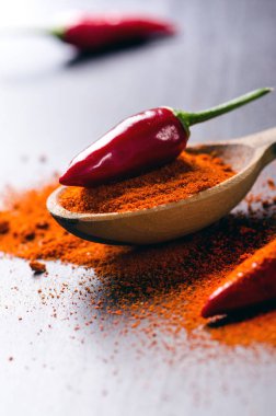 Soğuk kırmızı biber ile baharatlı, siyah ahşap bir masaya. Üzerinde bir tahta kaşık biber. Sebze. Sıcak yemek kavramı. 