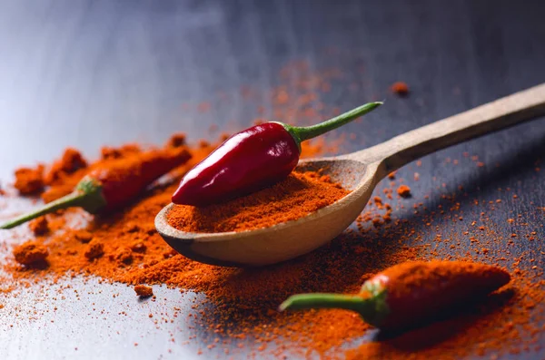 Red chilly peppers on a wooden, black table with spicy. Chilli on a wooden spoon. Vegetable. Concept of hot food.