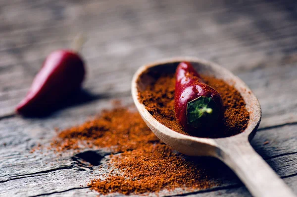 Rode chilipepers, pittige op een houten lepel. Groente op een donkere, houten tafel. Concept van warm voedsel. — Stockfoto