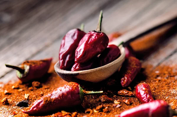 Rode chilipepers, pittige op een houten lepel. Groente op een donkere, houten tafel. Concept van warm voedsel. — Stockfoto