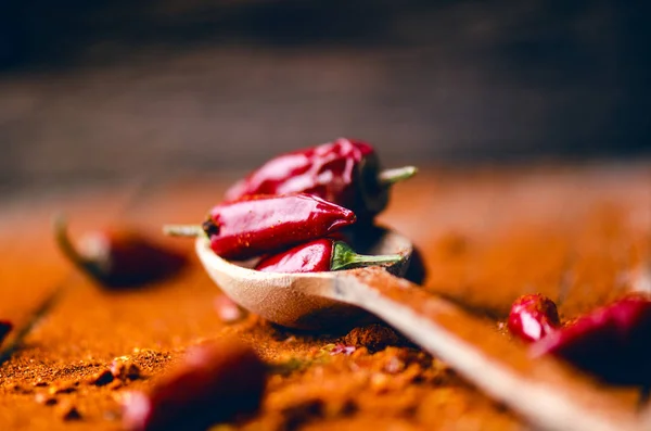 Červené chilli papričky, pikantní na dřevěnou lžící. Zelenina na tmavé, dřevěný stůl. Koncept teplé jídlo. — Stock fotografie