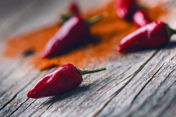 Rode chilipepers, pittige op een houten lepel. Groente op een donkere, houten tafel. Concept van warm voedsel. — Stockfoto