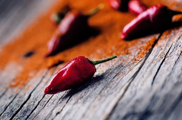 Červené chilli papričky, pikantní na dřevěnou lžící. Zelenina na tmavé, dřevěný stůl. Koncept teplé jídlo. — Stock fotografie